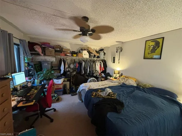 Carpeted bedroom with ceiling fan and a textured ceiling