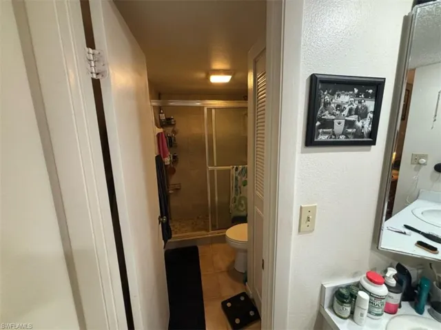 Bathroom featuring an enclosed shower, tile flooring, vanity, and toilet