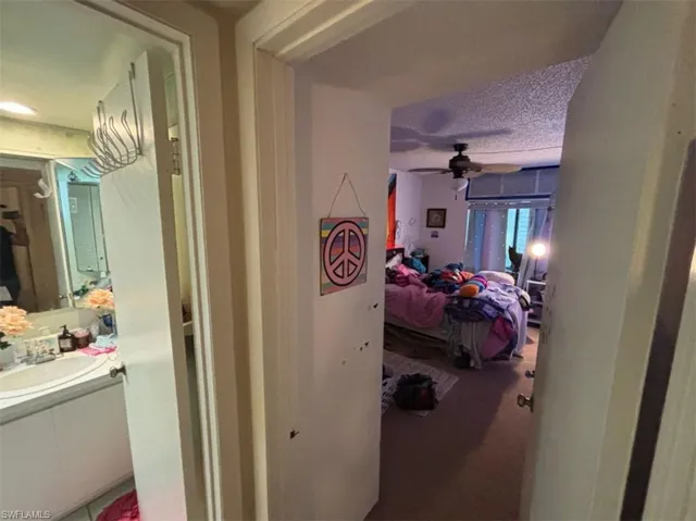 Carpeted bedroom featuring ceiling fan, sink, and a textured ceiling