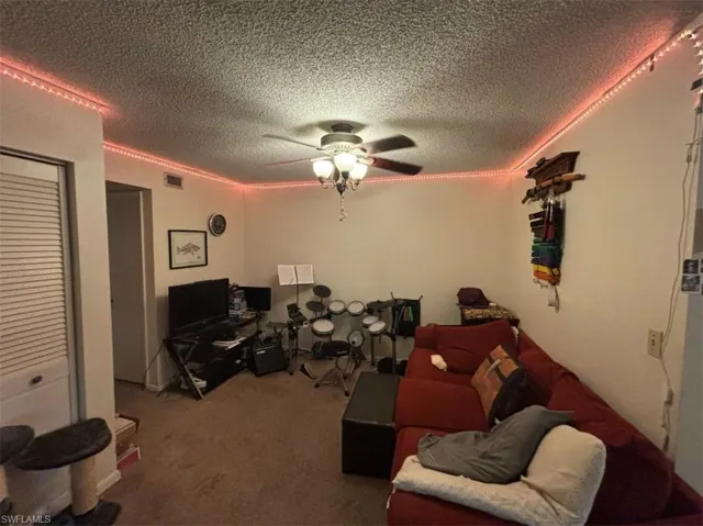 Carpeted living room featuring a textured ceiling and ceiling fan