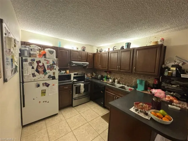Kitchen with tasteful backsplash, dishwasher, white refrigerator, stainless steel electric stove, and sink