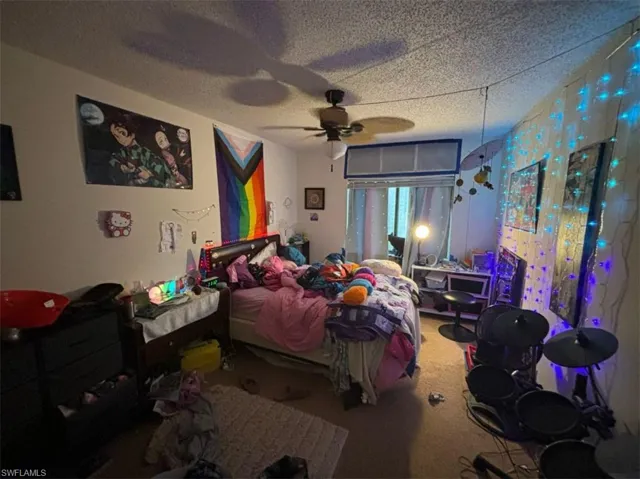 Bedroom featuring carpet, ceiling fan, and a textured ceiling
