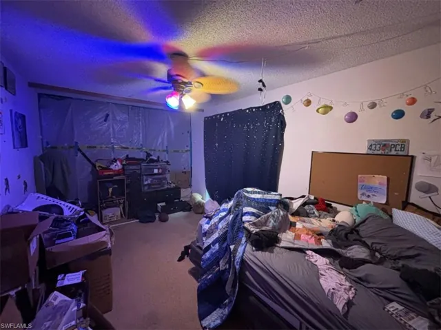Bedroom featuring a textured ceiling, carpet floors, and ceiling fan