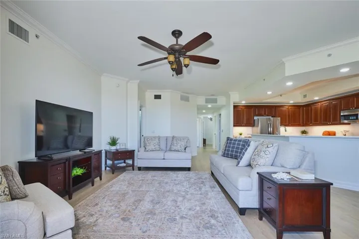 Living area with crown molding, ceiling fan, visible vents, and light wood-style flooring