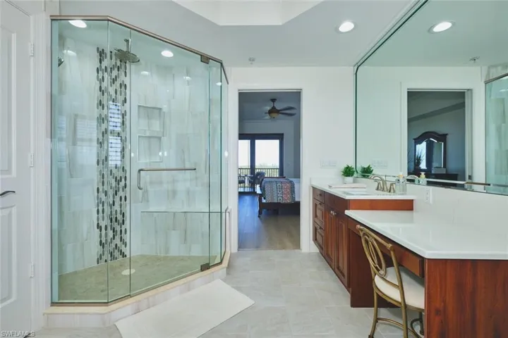 Bathroom featuring vanity, a stall shower, a ceiling fan, and ensuite bath