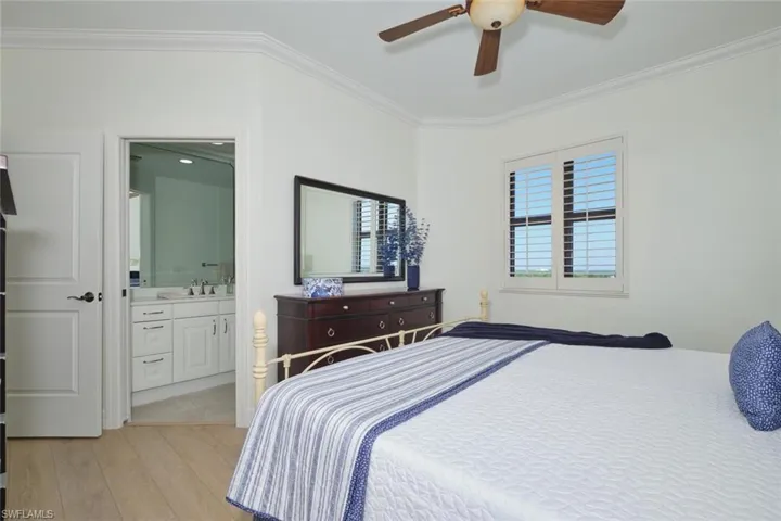 Bedroom featuring crown molding, ceiling fan, a sink, light wood-style flooring, and ensuite bath