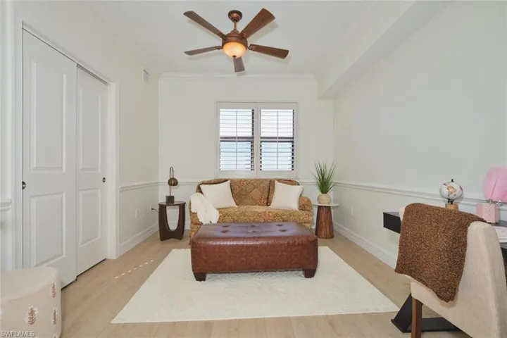 Living area featuring crown molding, light wood-style floors, ceiling fan, and baseboards