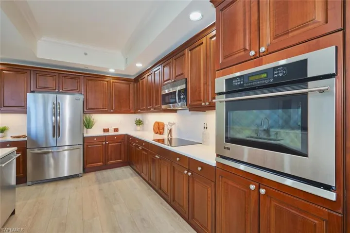Kitchen featuring crown molding, recessed lighting, light countertops, a raised ceiling, and stainless steel appliances
