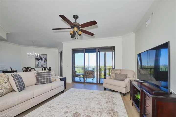 Living room featuring crown molding, ceiling fan with notable chandelier, and light wood-type flooring