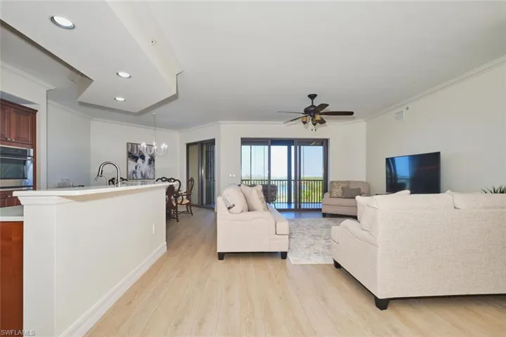 Living room featuring crown molding, recessed lighting, ceiling fan with notable chandelier, and light wood-type flooring