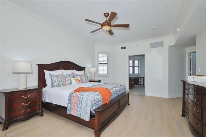 Bedroom with crown molding, visible vents, and light wood finished floors