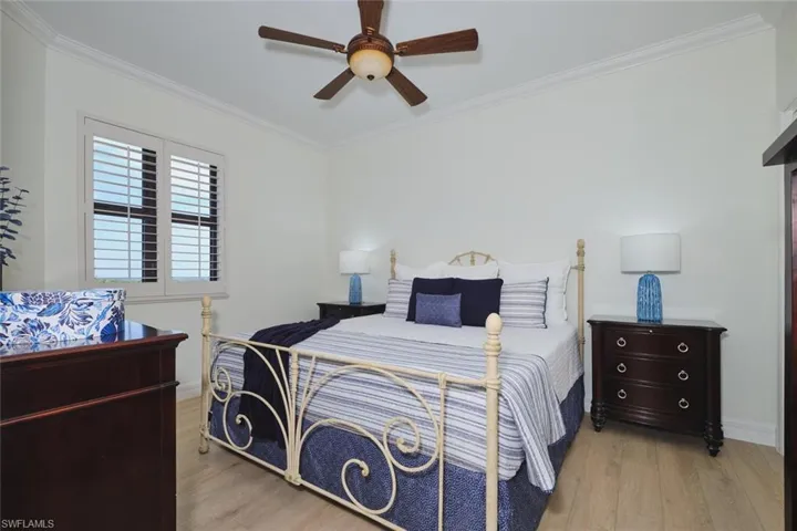 Bedroom featuring light wood-type flooring, ornamental molding, and ceiling fan