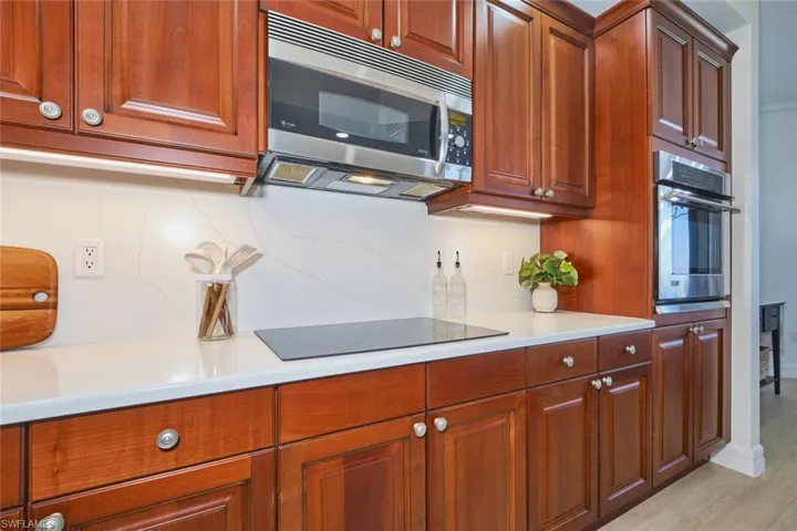 Kitchen featuring decorative backsplash, light wood-type flooring, light countertops, brown cabinets, and stainless steel appliances