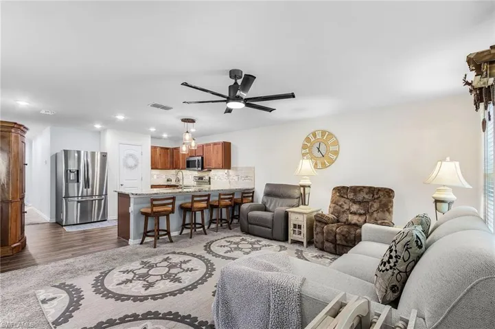 Living room with a ceiling fan, recessed lighting, and dark wood-style floors
