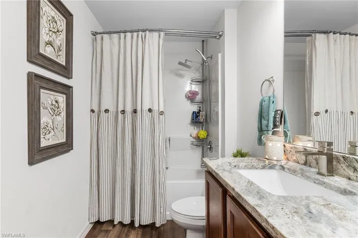 Full bath with vanity, dark wood-type flooring, and shower / bath combination with curtain