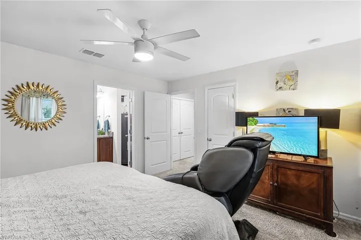 Bedroom featuring light colored carpet, a ceiling fan, and a desk