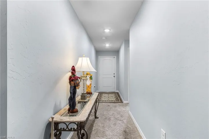 Doorway featuring carpet and a textured wall