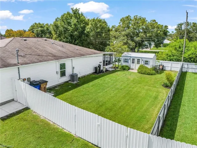Fenced backyard featuring an outdoor structure and view of scattered trees