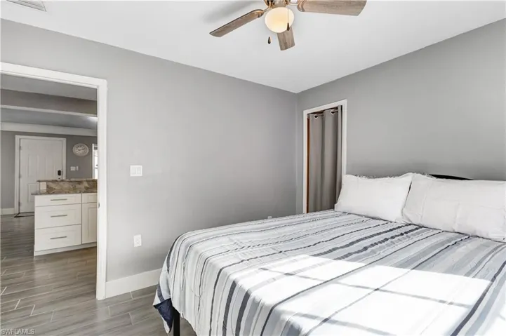 Room featuring light gray walls, wood-finish flooring, and a ceiling fan with integrated lighting