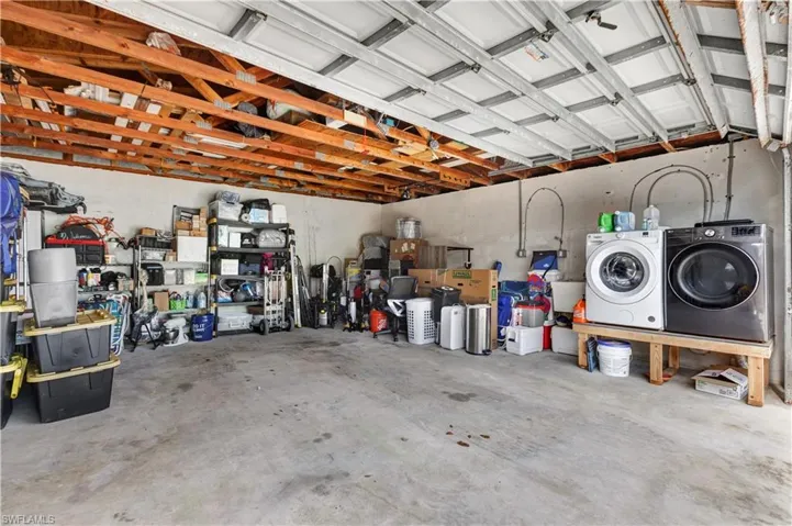 Attached garage with exposed wood ceiling joists and concrete flooring