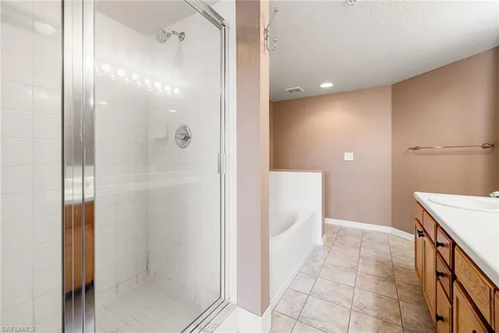 Bathroom featuring separate shower and tub, vanity, a textured ceiling, and tile floors