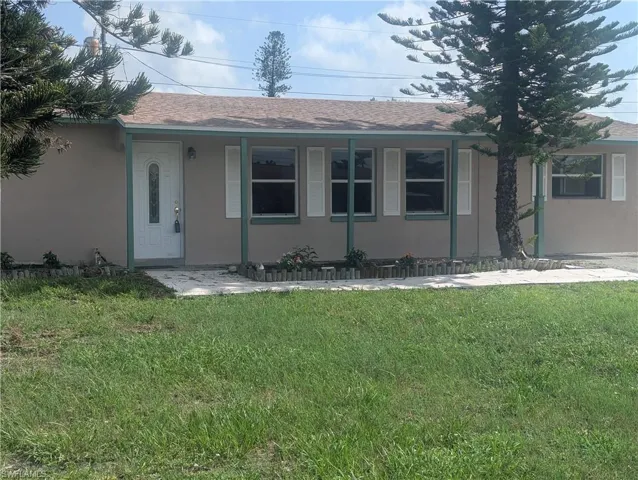 Single story home featuring a front yard, roof with shingles, and stucco siding