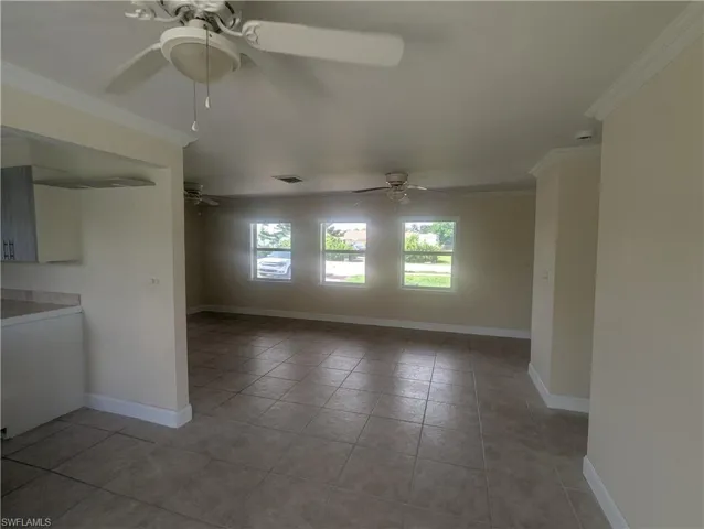 Tiled spare room with ceiling fan and ornamental molding