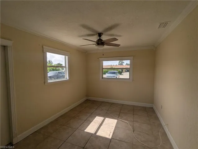Unfurnished room with crown molding, a textured ceiling, light tile patterned flooring, and a ceiling fan