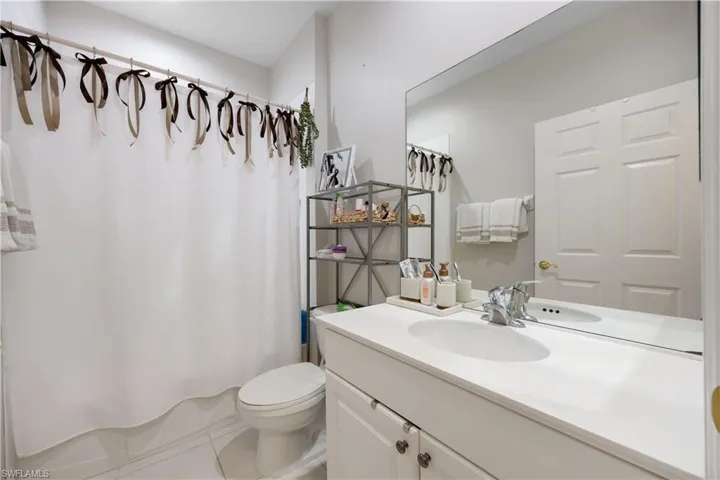 Bathroom with tile patterned floors, a shower with curtain, vanity, and toilet