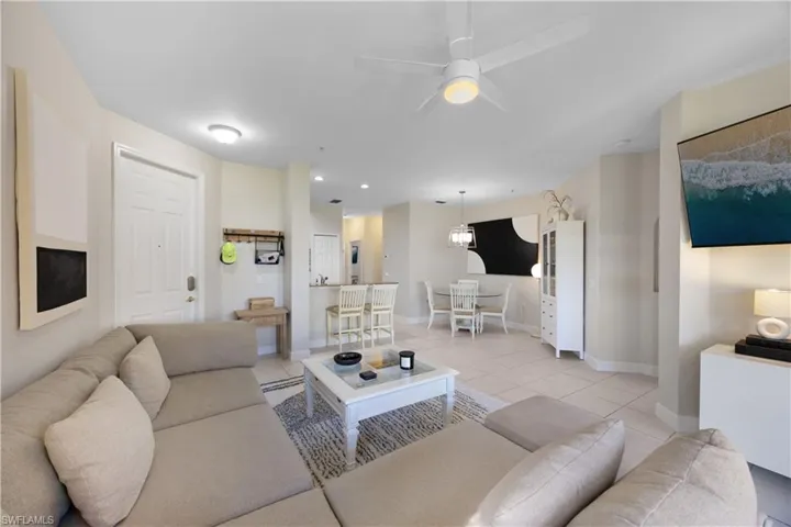 Tiled living room with ceiling fan with notable chandelier