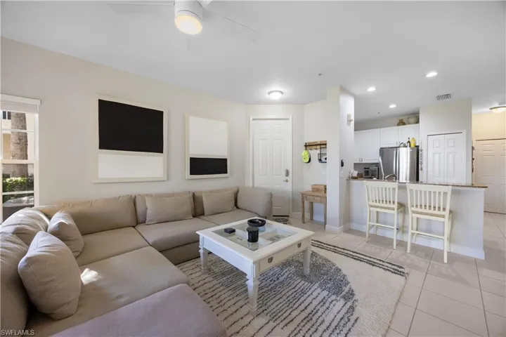 Living room with ceiling fan and light tile patterned flooring