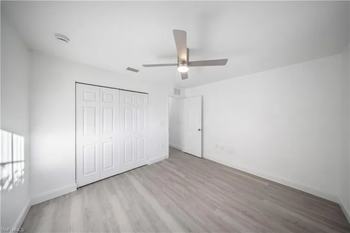 Unfurnished bedroom featuring a closet, light wood-style flooring, and a ceiling fan