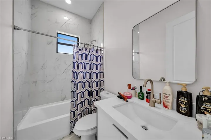Full bathroom featuring toilet, shower / tub combo with curtain, and vanity