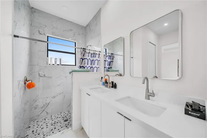 Bathroom featuring tiled shower and vanity