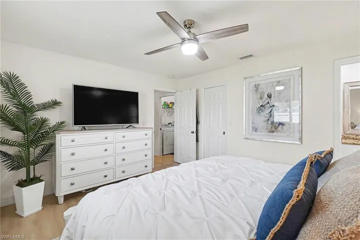 Bedroom featuring a ceiling fan, light wood finished floors, and washer / dryer