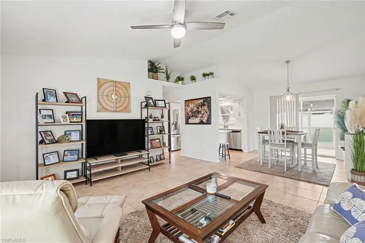 Living room with ceiling fan, vaulted ceiling, and light tile patterned floors