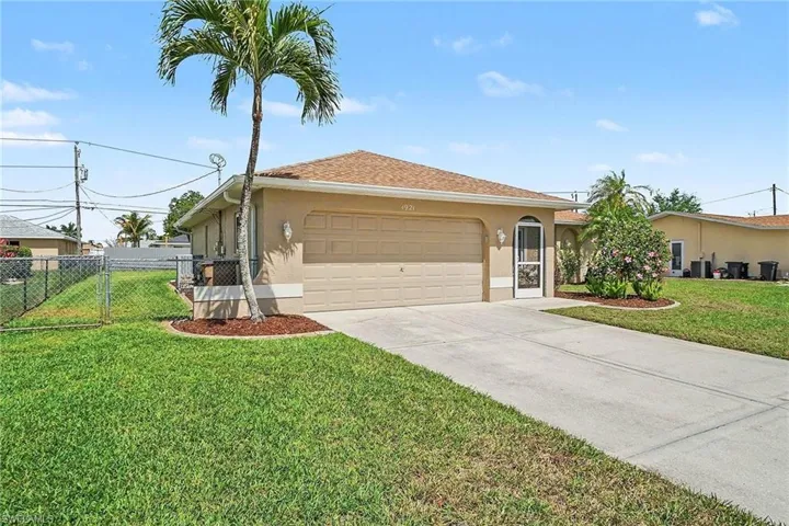 View of front of house with stucco siding, driveway, an attached garage, and a gate