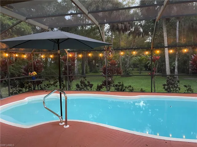 Swimming pool featuring a lanai, a yard, and a sunroom