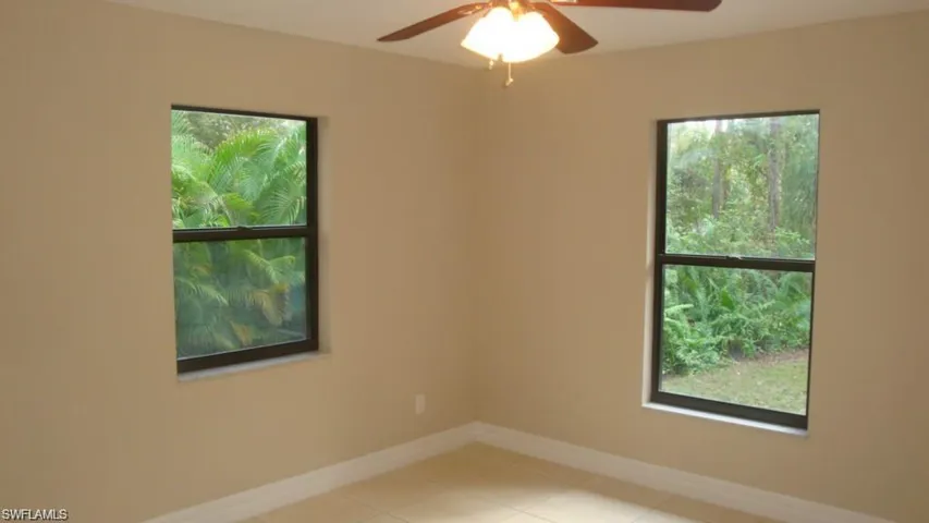 Empty room with plenty of natural light, tile patterned floors, and ceiling fan