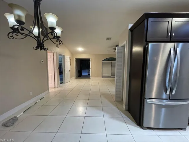 Kitchen featuring freestanding refrigerator, light tile patterned floors, a chandelier, pendant lighting, and vaulted ceiling