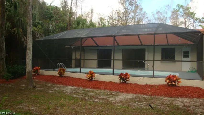 Rear view of house featuring a lanai, a sunroom, and an outdoor pool