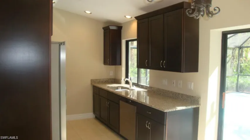 Kitchen featuring light stone counters, stainless steel dishwasher, dark brown cabinetry, recessed lighting, and light tile patterned flooring