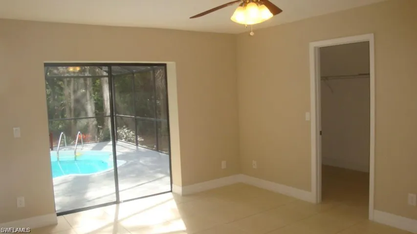 Unfurnished bedroom featuring access to outside, a spacious closet, light tile patterned flooring, and ceiling fan