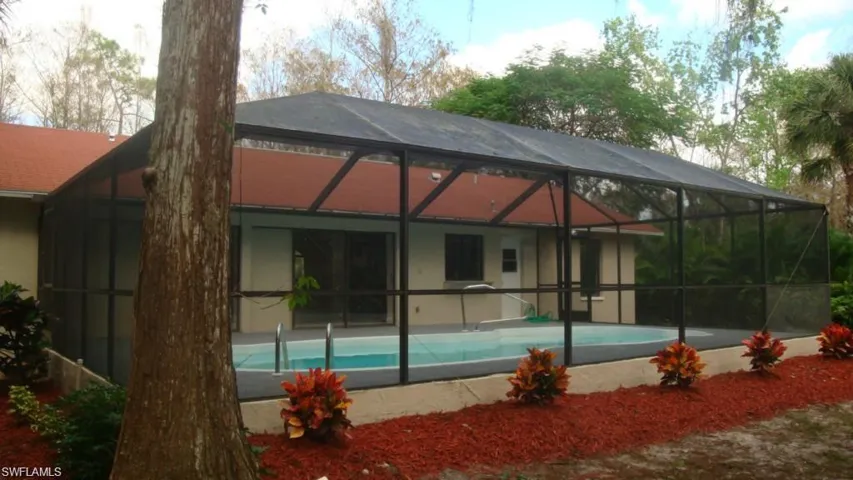 Rear view of property featuring an outdoor pool, a sunroom, and a lanai