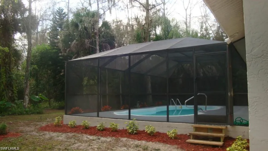 Swimming pool featuring a lanai, a sunroom, and view of wooded area