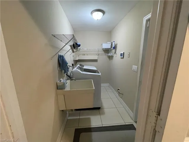 Laundry room featuring light tile patterned flooring and washing machine and clothes dryer
