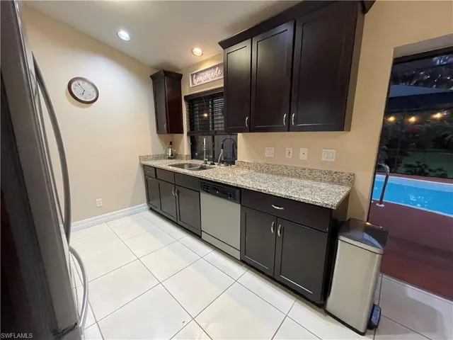 Kitchen with light stone counters, stainless steel appliances, light tile patterned flooring, and recessed lighting