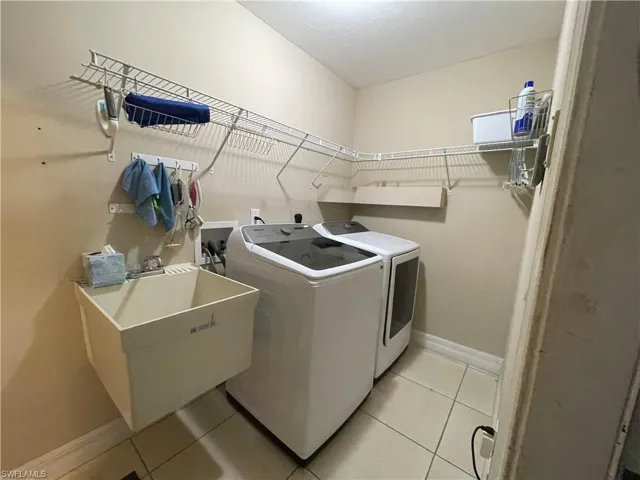 Laundry room featuring light tile patterned flooring and washing machine and clothes dryer