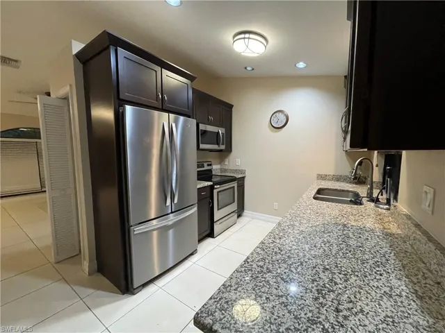 Kitchen featuring light stone countertops, appliances with stainless steel finishes, light tile patterned flooring, and recessed lighting