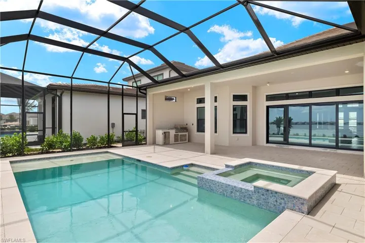 View of swimming pool with glass enclosure, an in ground hot tub, a patio, and area for grilling